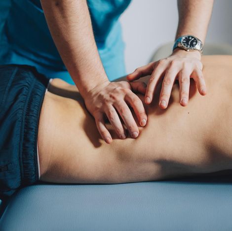 Physiotherapiebehandlung - Ausschnitt von Rücken der massiert wird 